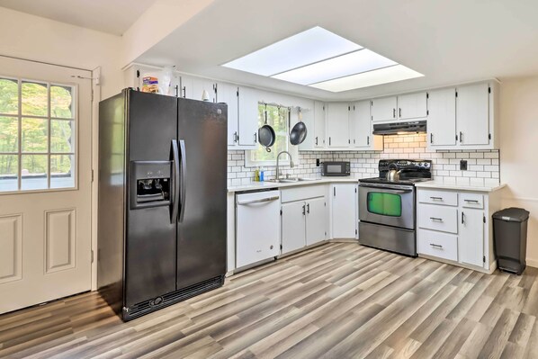 Enjoy cooking in this well-equipped kitchen with a refrigerator, microwave, stove, and sink.