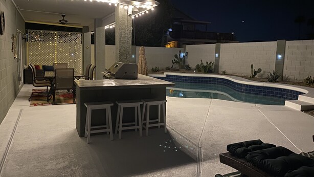 An outdoor patio with a pool, bar area, and seating. - Free Heated Pool! No pet fee!!  Electric vehicle charger in garage.  (Phoenix)