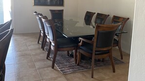 A dining room with a glass table surrounded by six chairs, a ceiling fan, and a painting on the wall. - Free Heated Pool! No pet fee!!  Electric vehicle charger in garage.  (Phoenix)