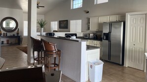 A spacious kitchen with a central island, white cabinetry, a stainless steel refrigerator, and a dining area with bar stools. - Free Heated Pool! No pet fee!!  Electric vehicle charger in garage.  (Phoenix)