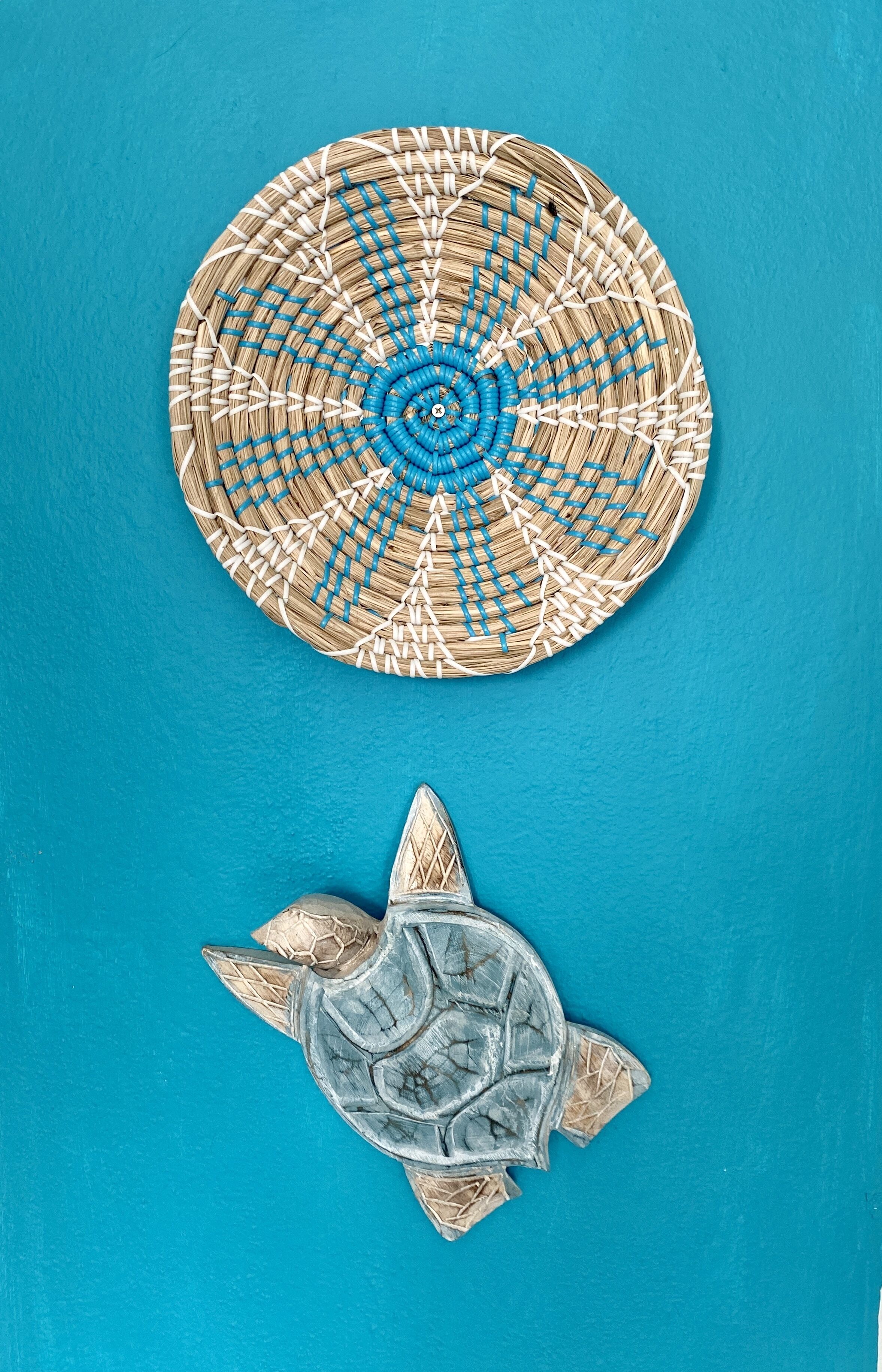 A circular woven mat with a blue spiral pattern and a turtle sculpture.