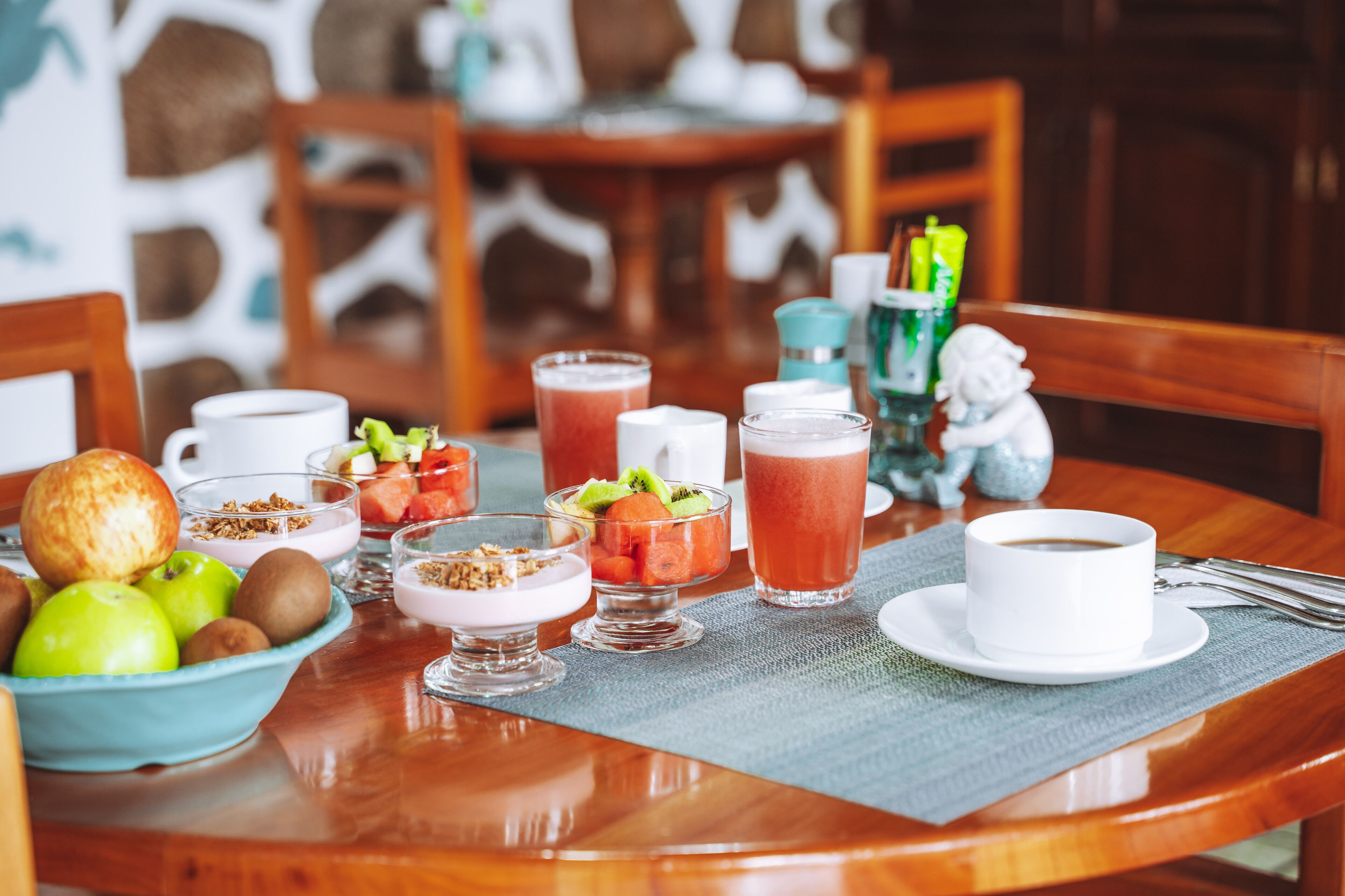 Ein Esstisch mit verschiedenen Speisen, darunter Obst, Joghurt und einer Kaffeetasse.