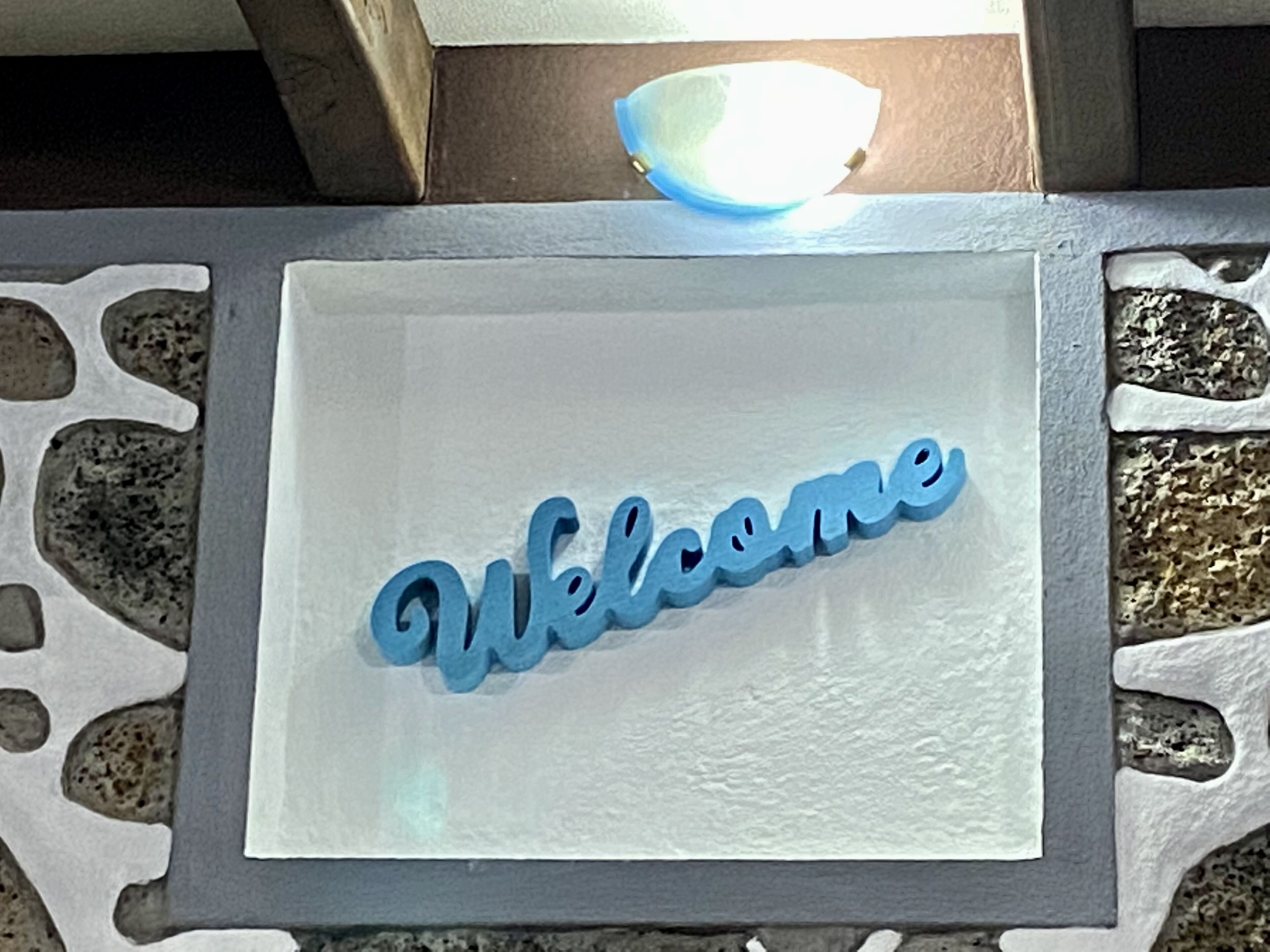 A welcome sign with a textured background and a stone-like border.