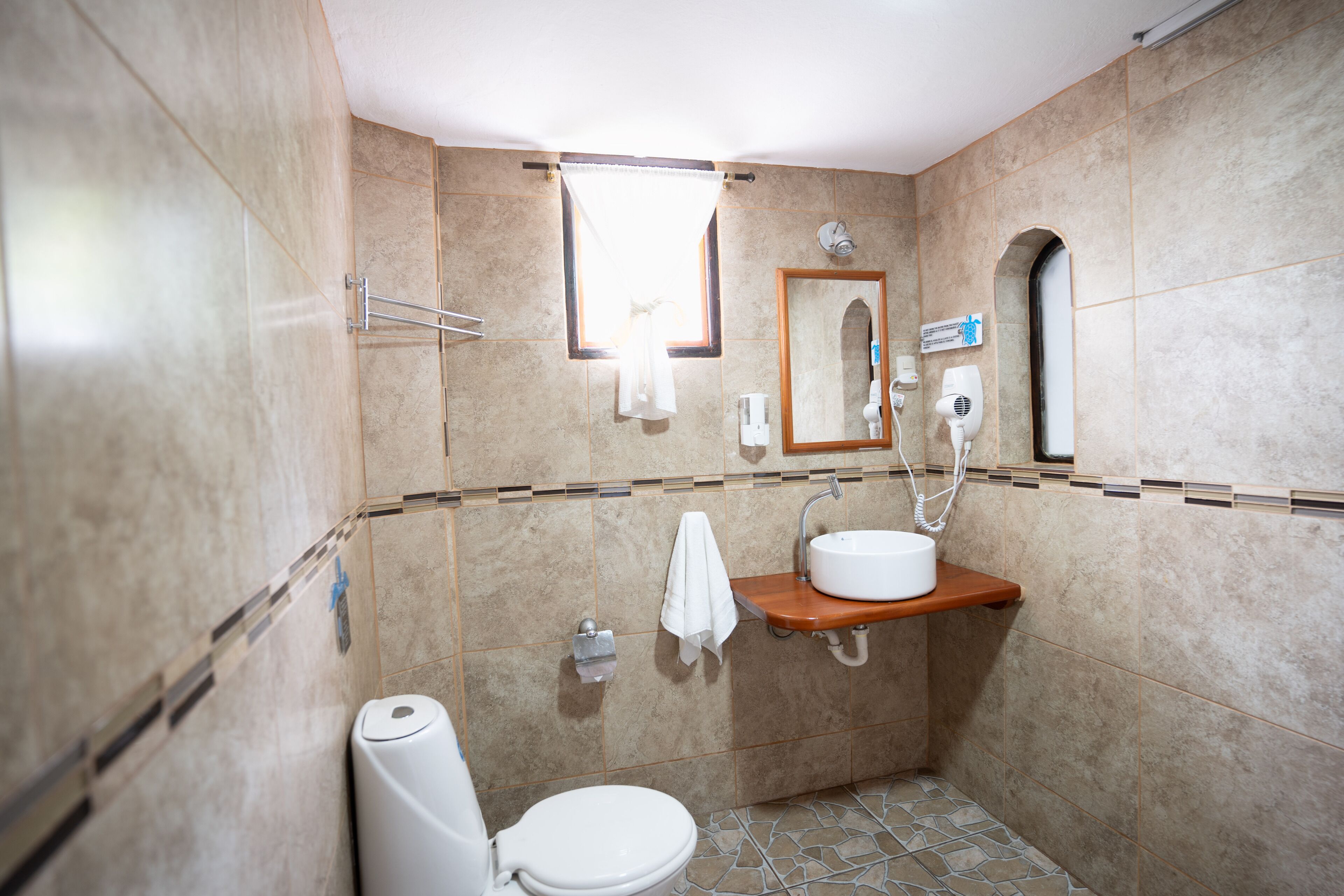 Une salle de bain comprenant des toilettes, un lavabo, un miroir, un porte-serviettes et un espace douche.