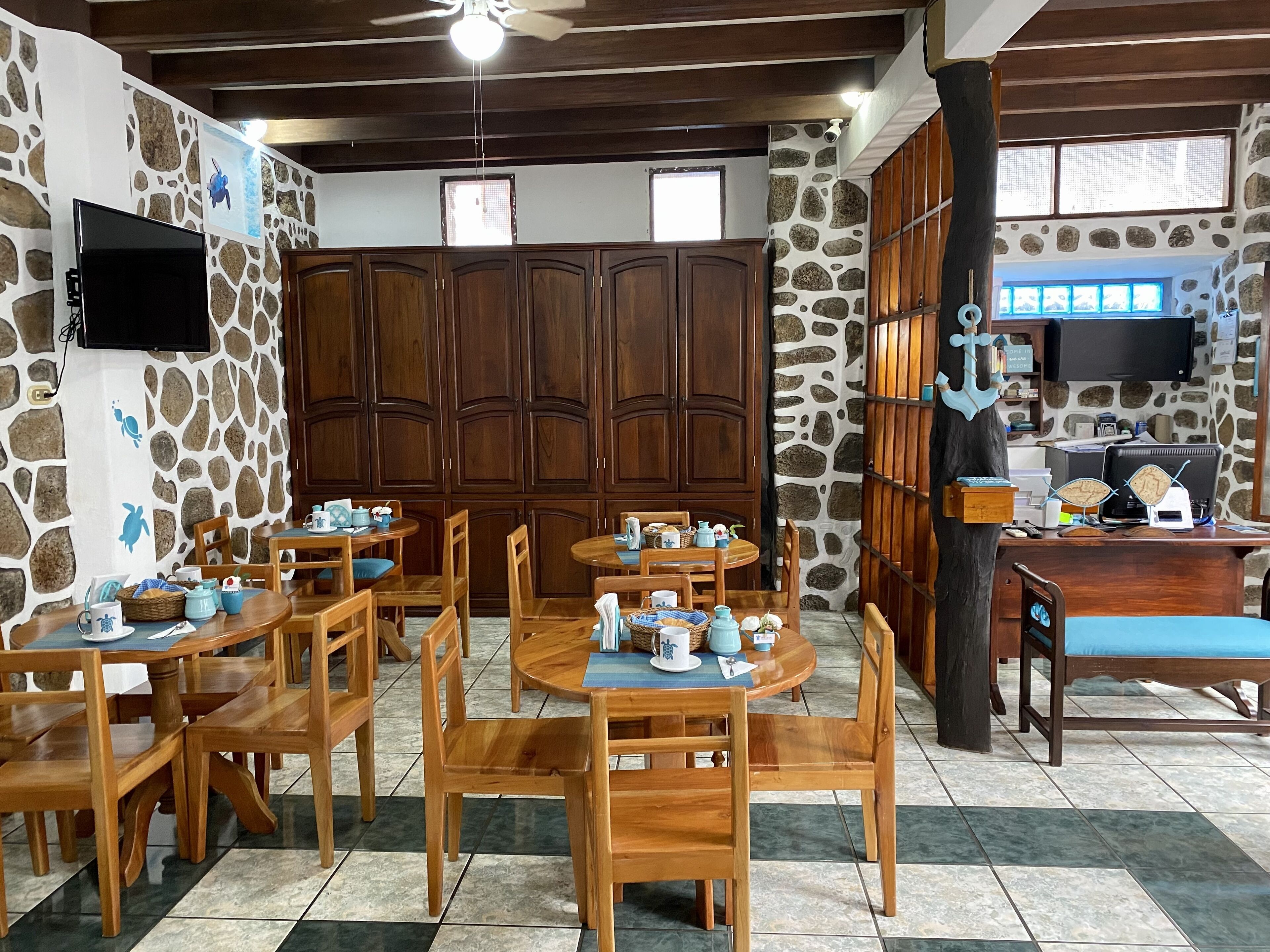Un comedor con mesas y sillas de madera, paredes de piedra y un televisor montado en la pared.