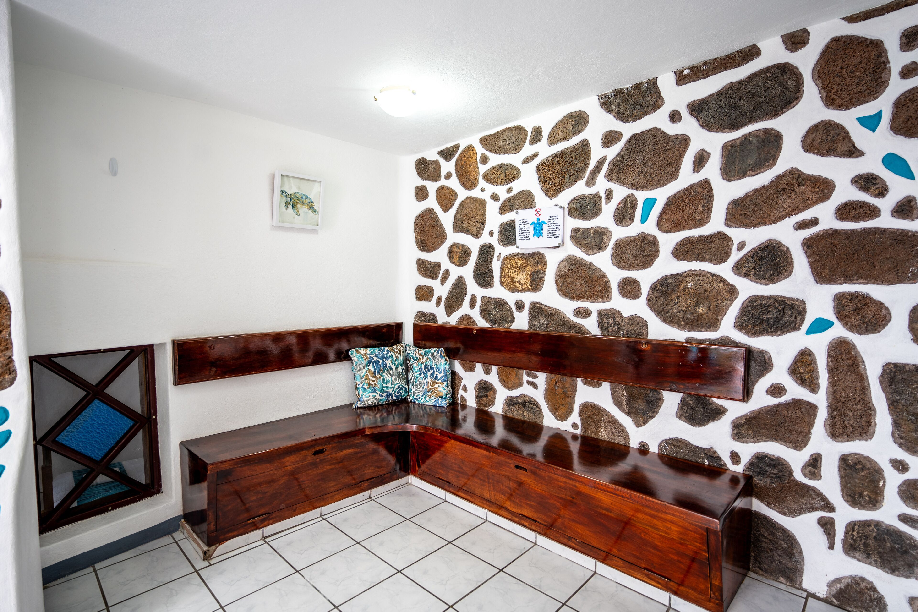 Angolo salotto con panchina in legno e parete in pietra.