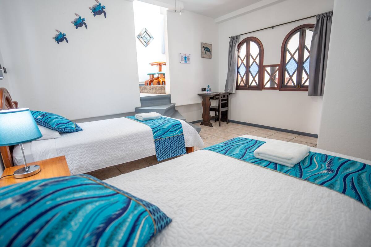 Ein Hotelzimmer mit zwei Betten, einem Schreibtisch und einem Fenster mit Vorhängen.