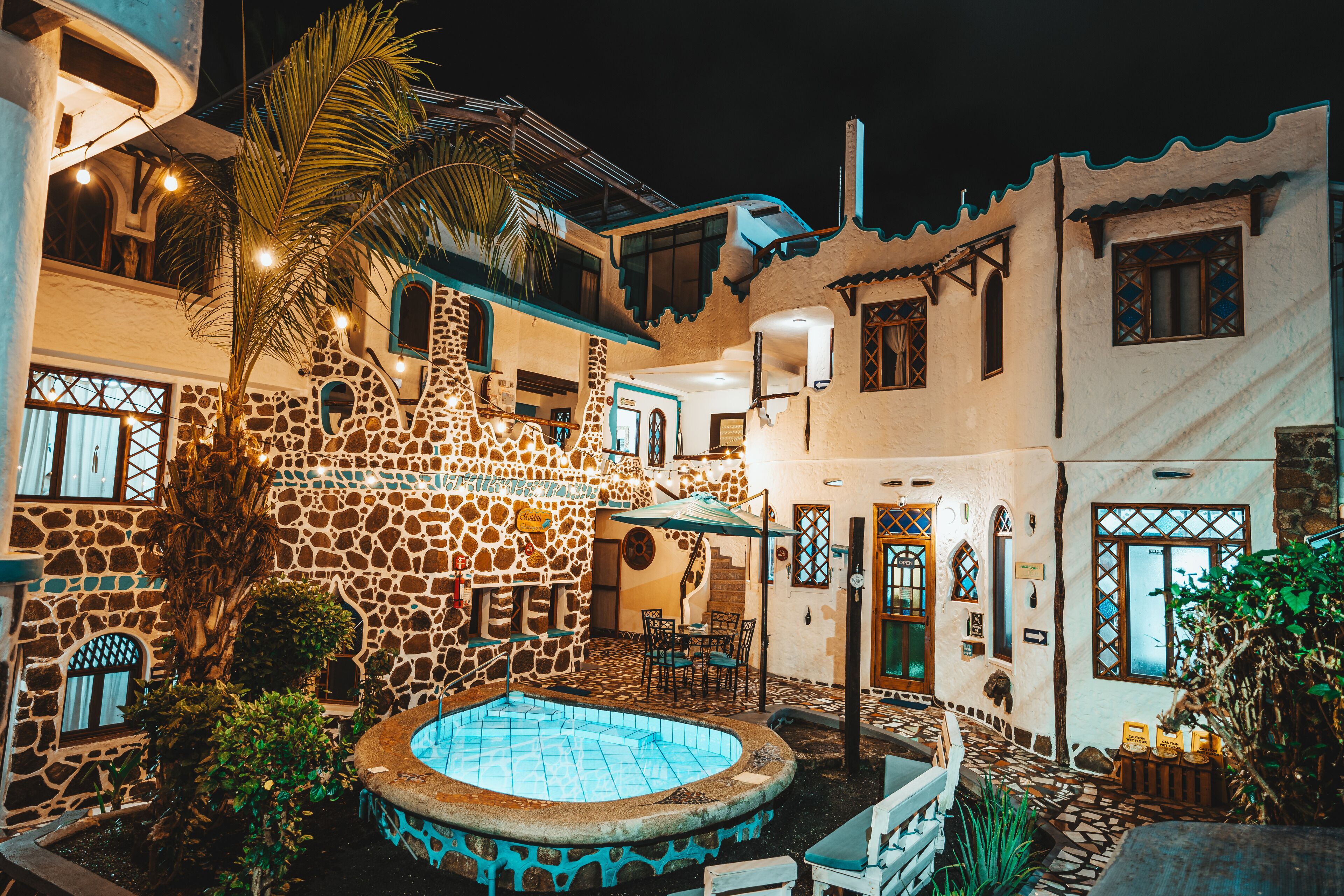 A courtyard with a swimming pool, stone walls, and a palm tree.