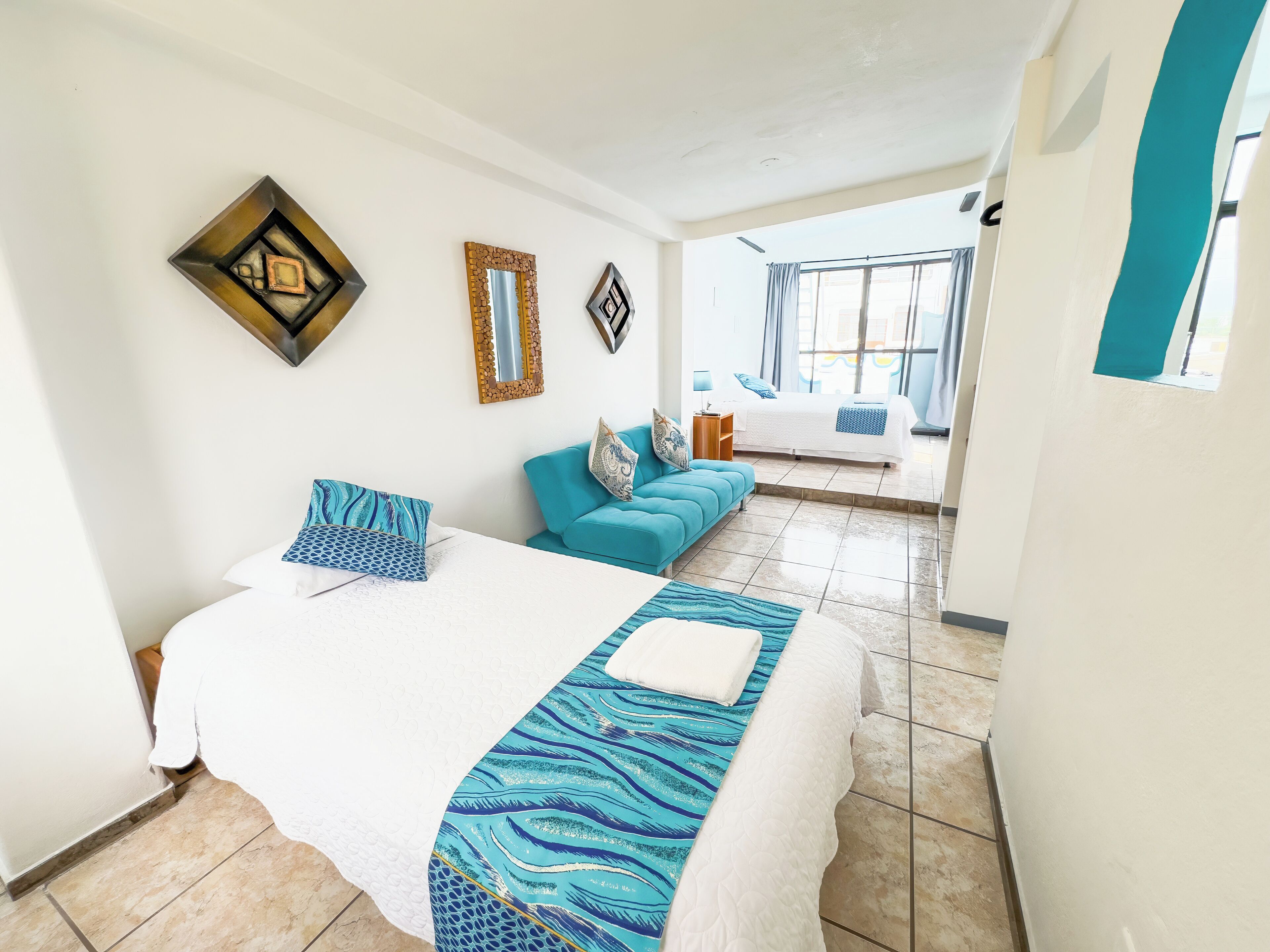 A hotel room with a bed, a sofa, and a window.