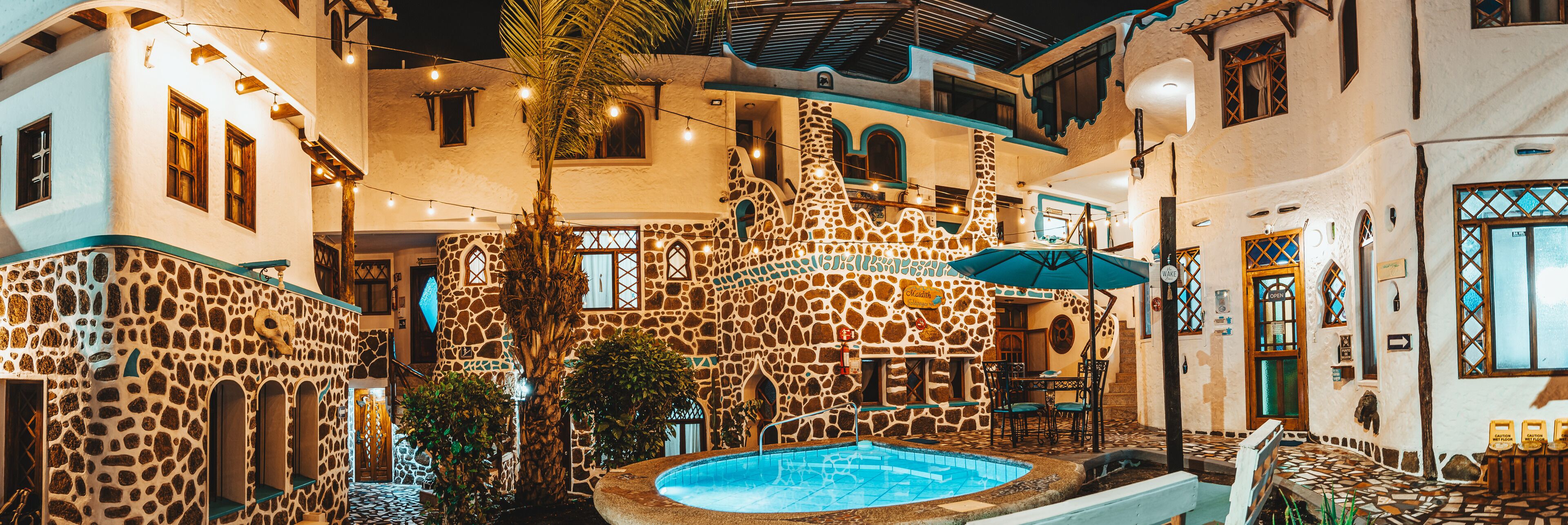 A courtyard with a swimming pool, stone buildings, and string lights.