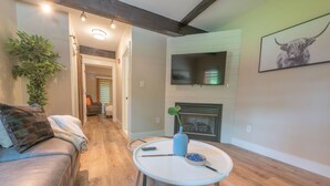 Una sala de estar con sofá, mesa de centro, chimenea y televisor.