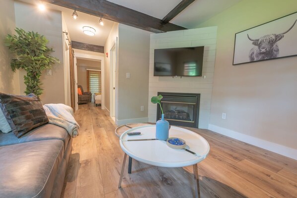A living room with a sofa, a coffee table, a fireplace, and a TV.