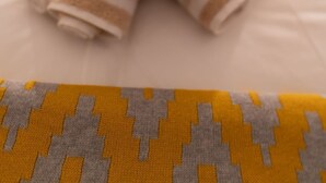 Una cama con un edredón a rayas y un osito de peluche.