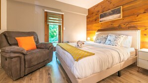 Un dormitorio con una cama, una silla, una mesita de noche y una pared de madera.