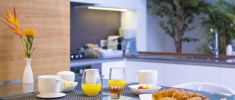 Ein Frühstückstisch mit Croissants, Orangensaft und Kaffeetassen in einem modernen Hotelzimmer.