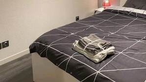A bedroom with a bed, a red rose decoration, and a black pendant light.