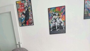 A grey sectional sofa with a white throw blanket, a white coffee table, and two framed artworks on the wall.