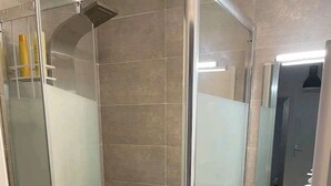 A modern bathroom with a glass-enclosed shower, a white sink, and a mirror above it.