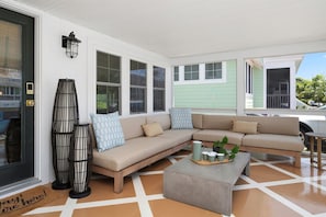 A covered porch with a beige sectional sofa, a small table with a tray of items, and a tall black lamp. - #9 Dog-Friendly 3BR Ocean-Block Cottage W/ Screened Porch & Sundeck in Rehoboth (Rehoboth Beach)