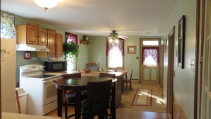 A kitchen with wooden cabinets, a stove, and a dining area with a table and chairs.