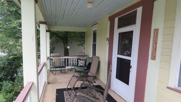 A covered porch with outdoor furniture, a door, and a window.