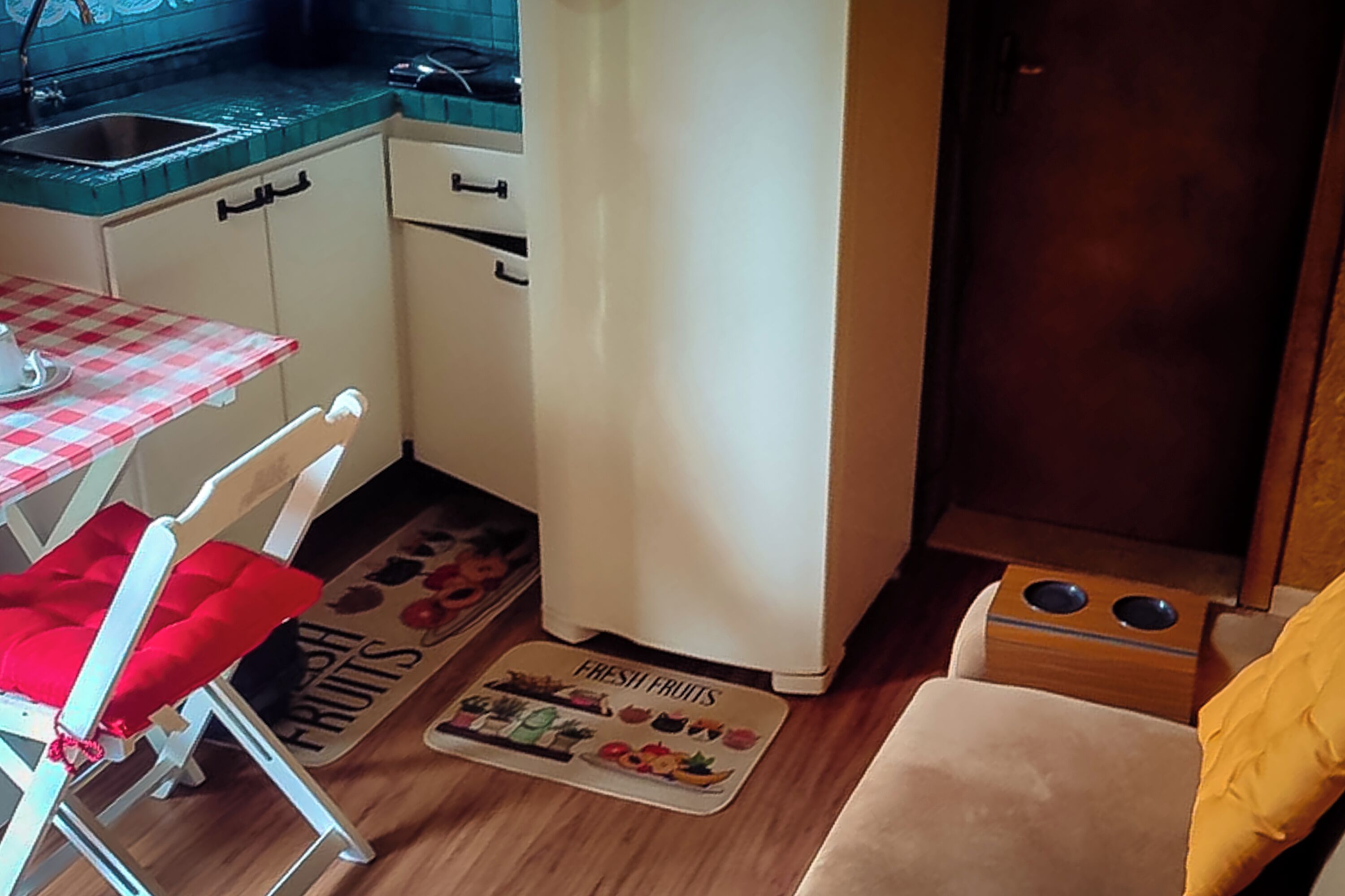 A compact kitchen with a refrigerator, a sink, and a dining area with a checkered tablecloth.