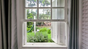 A window with a view of a garden, including a slide and greenery. - Pousada Casa de Campos Capivari by Concavus (Campos do Jordão)