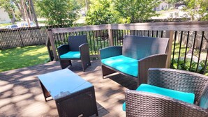 Una terraza de madera con muebles de mimbre y una pequeña mesa.