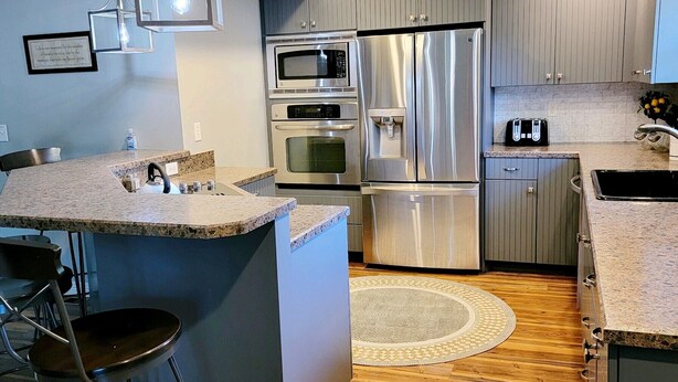 Una cocina moderna con electrodomésticos de acero inoxidable, una barra y suelo de madera.