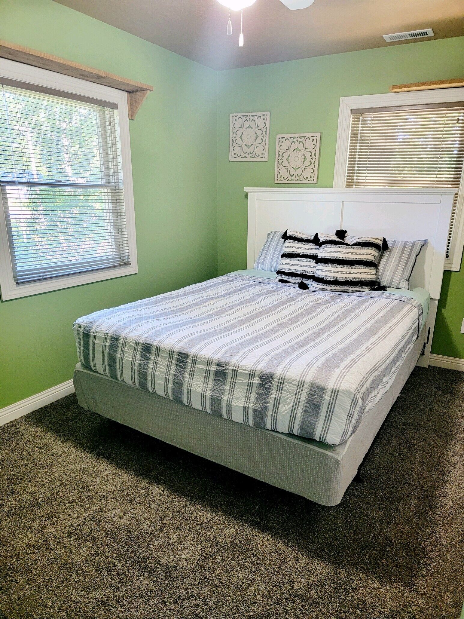 A bedroom with a bed, green walls, and a window with blinds.