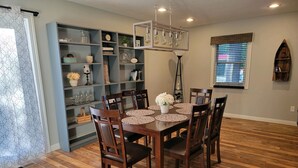 Un comedor con una mesa y sillas de madera, rodeado de estanterías con diversos objetos decorativos.