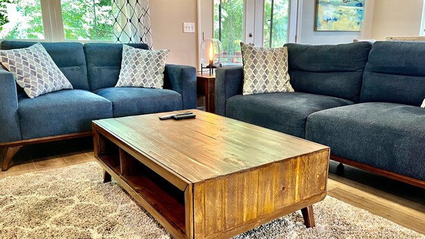 A living room with two dark blue sofas, patterned throw pillows, a wooden coffee table, and a beige carpet. - New Modern Home in the heart of Downtown Durham (Durham)
