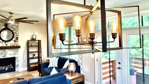 A living room with a blue sofa, a fireplace, a clock, and a ceiling fan. - New Modern Home in the heart of Downtown Durham (Durham)