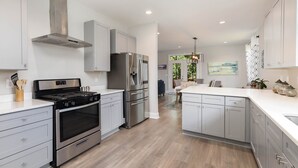 A modern kitchen with stainless steel appliances, white cabinetry, and a wooden floor. - New Modern Home in the heart of Downtown Durham (Durham)
