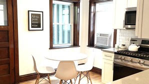 Una cucina moderna con un tavolo e sedie, un piano cottura, un forno a microonde e un cartello incorniciato appeso al muro.