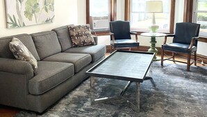 Un soggiorno con un divano grigio, due poltrone, un tavolino e una ventola a soffitto.