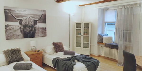 Un dormitorio con cama, mesita de noche, armario, ventana con cortinas y un cuadro en la pared.