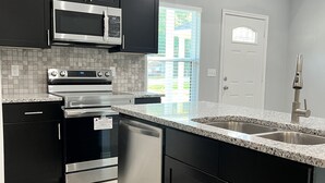 A modern kitchen with dark cabinets, stainless steel appliances, a granite countertop, and a view of the outside. - Beautiful home 5 minutes to Lake, water activities, shopping and restaurants (Montgomery)