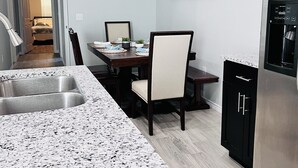 A modern kitchen with granite countertops, a dining area with a table and chairs, a refrigerator, and a painting on the wall. - Beautiful home 5 minutes to Lake, water activities, shopping and restaurants (Montgomery)
