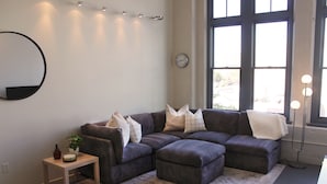 Una sala de estar moderna con un sofá modular, una mesita de madera pequeña y un ventanal que proporciona luz natural.