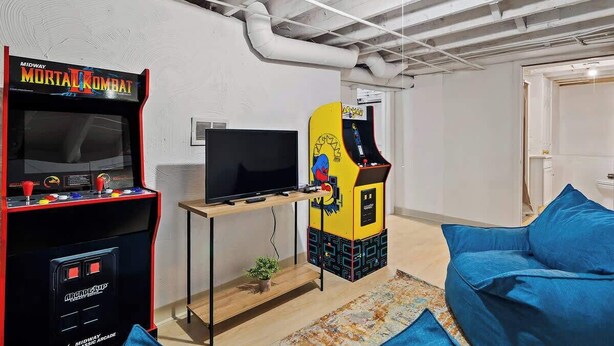 Een kamer met een spelconsole, een televisie en een blauwe bank.