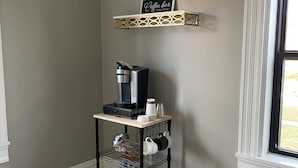 A kitchen area with a coffee maker on a shelf, a rug, and a window with a view.