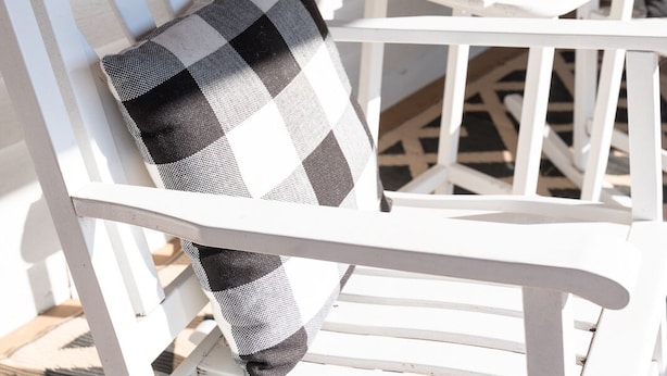 A white wooden chair with a black and white checkered cushion.