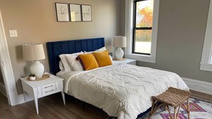 A bedroom with a bed, two nightstands, a window, and a rug.