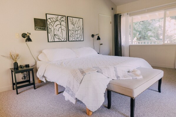 A bedroom with a bed, a bedside table, a lamp, and artwork on the wall.