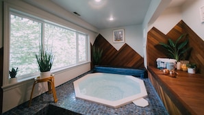 A spa room with a hot tub, wooden accents, and large windows. - Iconic Union Skyhouse with Hood Canal views (Union)