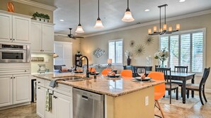 A spacious kitchen with white cabinetry, a central island, and a dining area with a table and chairs. - Indio Home w/ Private Pool & Community Amenities (Indio)