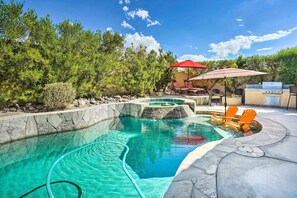 Piscina com hidromassagem, rodeada por um deck de pedra e mobiliário para áreas externas.