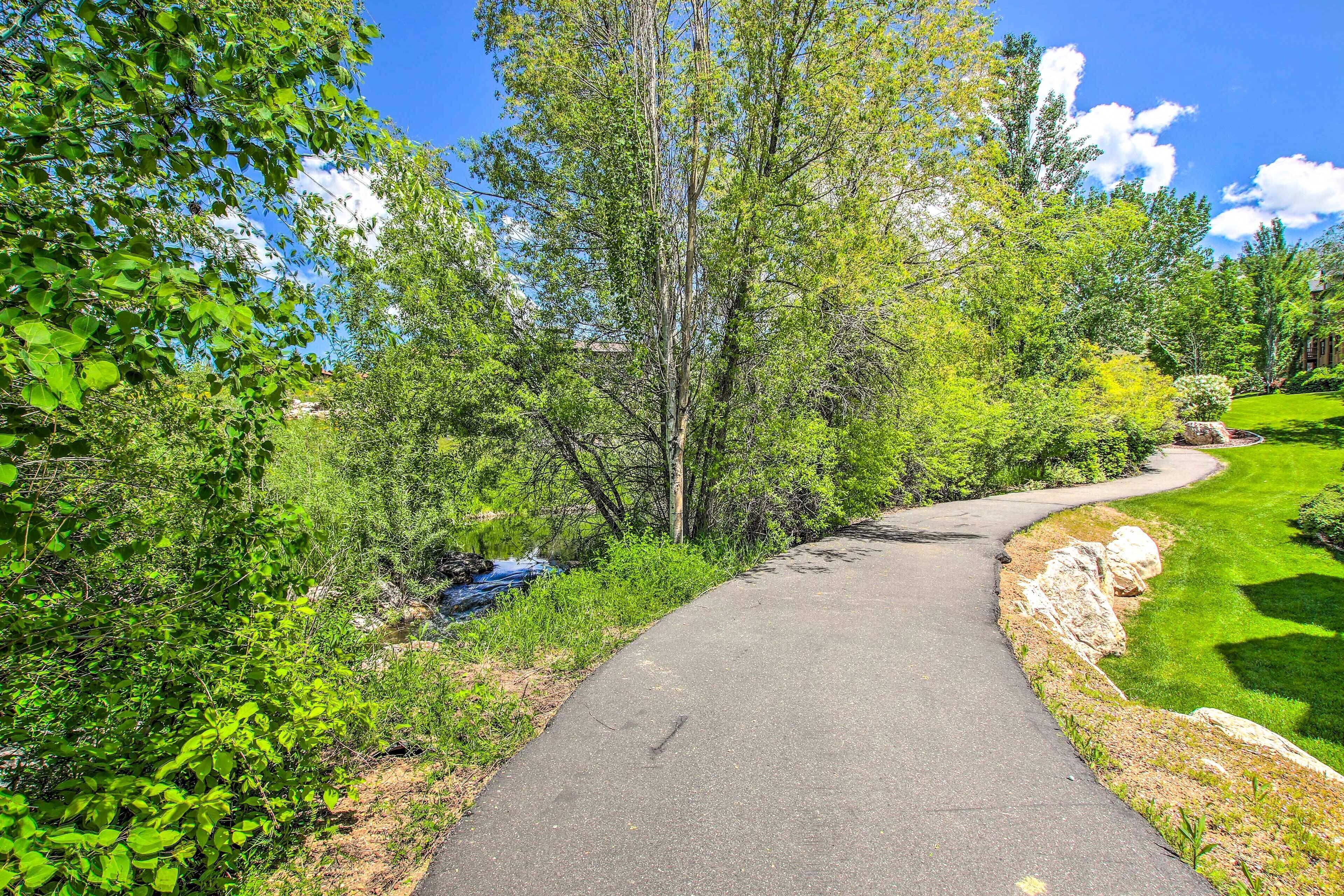 Un sentier dallé, bordé d’une végétation luxuriante et d’arbres.