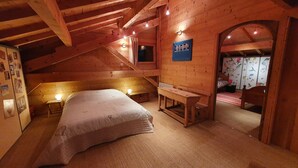 A cozy wooden cabin bedroom with a bed, a desk, and a chair.